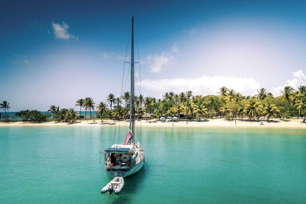 00-AdobeStock_208682310-zero-Caribbean- A boat anchored in a calm and pristine green water.