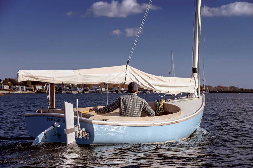 A man sailing a dinghy with an electric motor