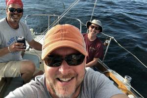 3 men in a selfie photo on the water