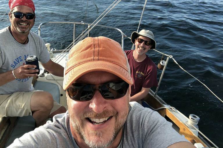 3 men in a selfie photo on the water