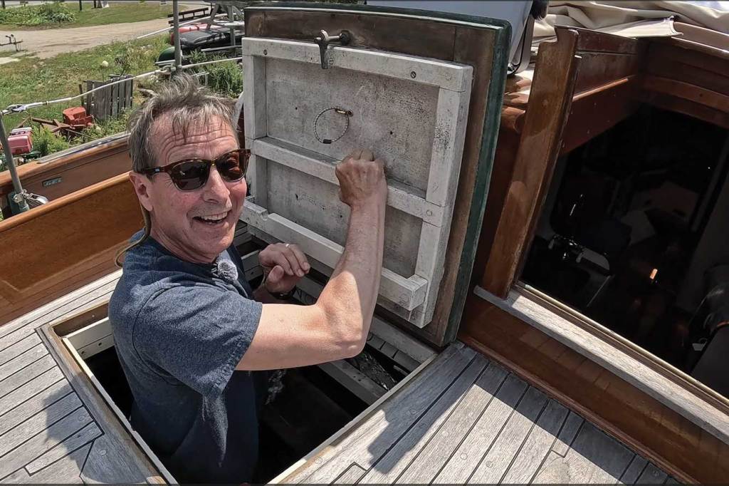 A man popping out of the hatch on a boat.