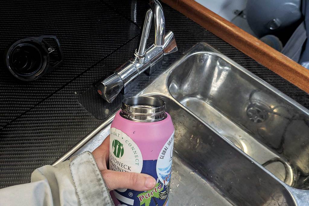 A small sink with a pink water bottle filling with water