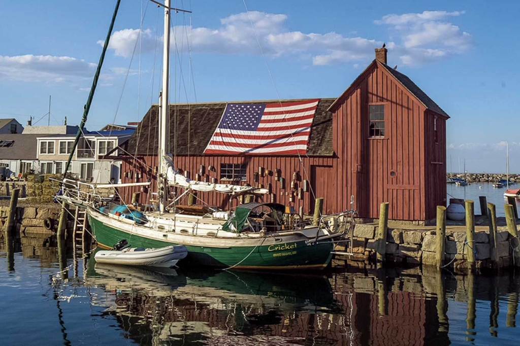 A brown boat house with buoys and an American flag hanging off it.